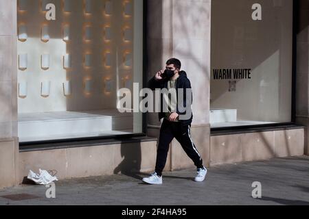 Mann am Telefon, der an Zara-Schaufenster vorbeiging, Barcelona, Spanien. Stockfoto