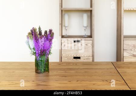 Schöne frische natürliche lila lila liatris Blume Bouquete in Glas auf ländlichen Holztisch gegen Wand mit Schrank Regal. Rustikale Landschaft Stockfoto
