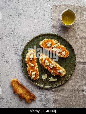 Draufsicht appetitlich frische Toast mit Marmelade und Ziegenkäse Serviert auf Teller in der Nähe von Krug mit Bio-Olivenöl Stockfoto