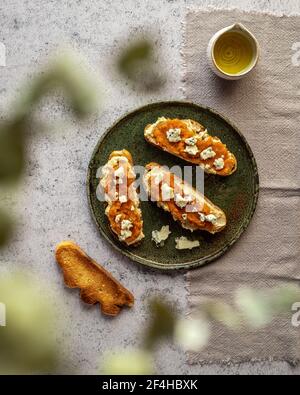 Draufsicht appetitlich frische Toast mit Marmelade und Ziegenkäse Serviert auf Teller in der Nähe von Krug mit Bio-Olivenöl Stockfoto