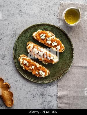 Draufsicht appetitlich frische Toast mit Marmelade und Ziegenkäse Serviert auf Teller in der Nähe von Krug mit Bio-Olivenöl Stockfoto