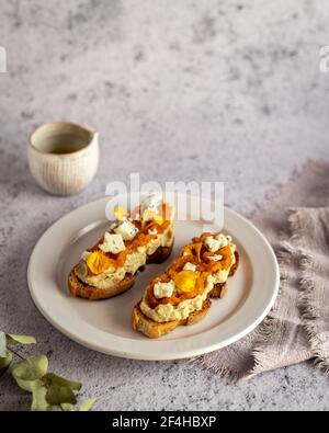 Von oben appetitlich frische Toast mit Marmelade und Ziegenkäse Serviert auf Teller in der Nähe von Krug mit Bio-Olivenöl Stockfoto