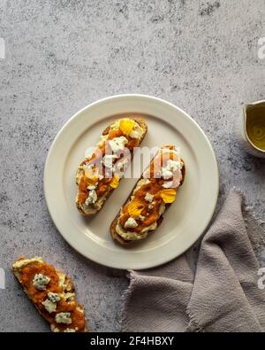 Draufsicht appetitlich frische Toast mit Marmelade und Ziegenkäse Serviert auf Teller in der Nähe von Krug mit Bio-Olivenöl Stockfoto