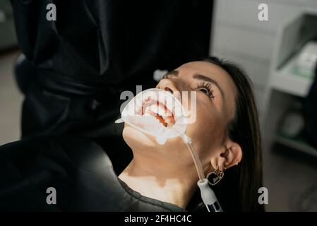 Crop unkenntlich Zahnarzt bei der Behandlung von Zähnen der Frau mit Speichel Auswerfer und Aufrollautomatik im Mund Stockfoto