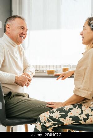 Seitenansicht des Inhalts Erwachsener Paar sitzt an der Theke in Küche und genießen aromatischen Kaffee beim Frühstück und suchen Aufeinander zu Stockfoto