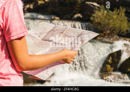 Nicht erkennbare Reisende Frau, die mit einer Papierkarte in der Nähe des Wasserfalls im Nationalpark Ordesa y Monte Perdido steht und sich während des Urlaubs in Pyren orientiert Stockfoto