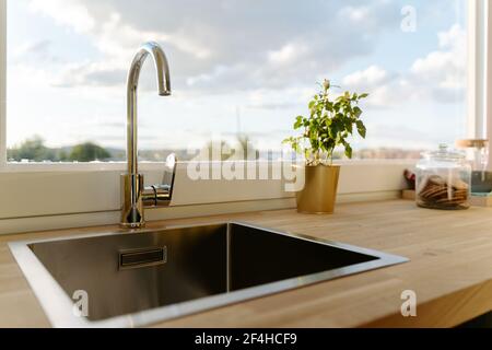 Quadratisches Waschbecken auf Holztischplatte in der Nähe des Fensters Moderne Küche an sonnigen Tagen Stockfoto
