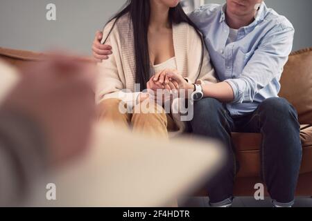 Crop unkenntlich Paar umarmt und hält die Hände während der geistigen Therapie Sitzung im Büro des Psychologen Stockfoto