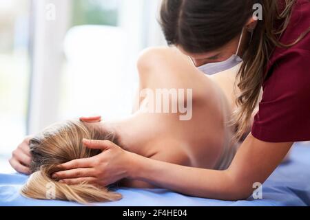 Physiotherapeutin in Maske hilft weiblichen Patienten Stockfoto