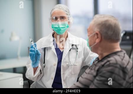 Ein älterer Mann erhält in der Klinik eine Impfung gegen das Covid 19 Coronavirus. Universelle Impfung der Bevölkerung Stockfoto