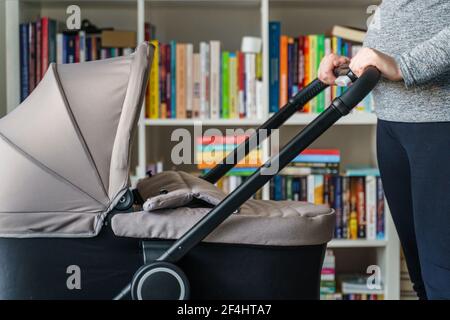 Nahaufnahme des Mittelabschnittes einer unbekannten schwangeren Frau aus Kaukasien in der Hand Ihr Bauch beim Überprüfen der Babykutsche - Mutterschaft und Schwangerschaft Mit Kinderwagen Eiter Stockfoto