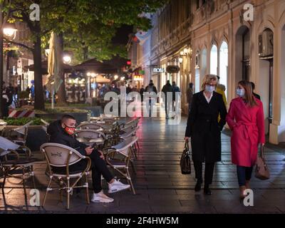 BELGRAD, SERBIEN - 19. OKTOBER 2020: Junger Mann mit seinem Smartphone am Tisch eines Café-Bar-Restaurants mit einer Gesichtsmaske während des Coronavirus CO Stockfoto