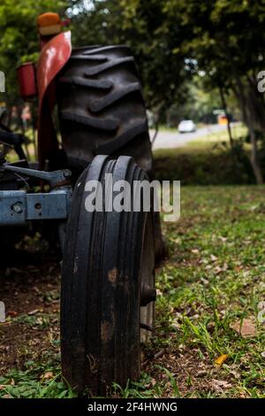 Abgenutzte Reifen einer sehr alten roten verlassenen Farm Traktor in einem Bauernhof auf dem Land Stockfoto