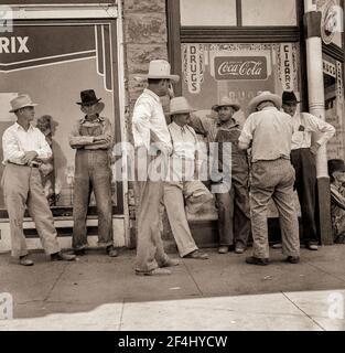 Dürrebauern säumen die schattige Seite der Hauptstraße der Stadt, während ihre Ernten auf den Feldern brennen. 'Hallo Bill, wann wird es regnen? August 1936. Foto von Dorothea lange. Stockfoto