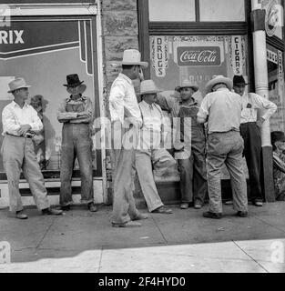 Dürrebauern säumen die schattige Seite der Hauptstraße der Stadt, während ihre Ernten auf den Feldern brennen. 'Hallo Bill, wann wird es regnen? August 1936. Foto von Dorothea lange. Stockfoto