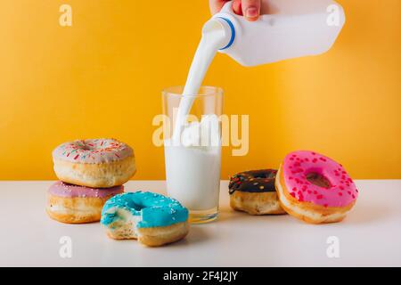 Süße Donuts mit Mann Hand Gießen Milch Stockfoto