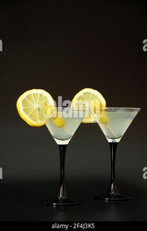 Zwei Gläser martini mit Oliven und Zitronenscheiben auf schwarzem Hintergrund. Nahaufnahme. Stockfoto