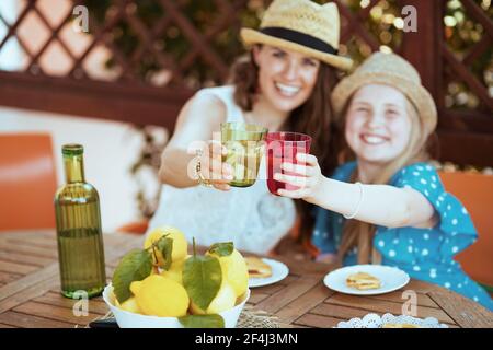 Nahaufnahme einer glücklichen Familie mit einer grünen Flasche Limonade und Teller von lokalen Bauernhof Zitronen klirenden Gläser und Mittagessen Auf der Terrasse des Gästehauses heiß Stockfoto