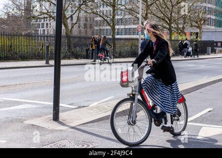 London, Großbritannien. März 2021, 21st. Eine Frau mit Gesichtsmaske als vorbeugende Maßnahme gegen die Ausbreitung von covid 19 fährt ein Fahrrad in der Nähe von Tower Hill.die tägliche Zahl der COVID-19 Todesfälle in Großbritannien sank auf 33 am Sonntag 21st März 2021 Quelle: SOPA Images Limited/Alamy Live News Stockfoto