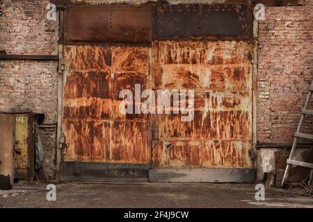 Rostige große Tore einer verlassenen industriellen Garage, Ziegelmauern. Stockfoto