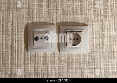 Buchse und Buchse für das TV-Antennenkabel an der beigefarbenen Wand. Stockfoto