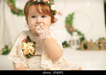 Portrait eines kleinen Geburtstagskindes mit dem ersten Kuchen. Den ersten Kuchen essen. Kuchen zerschlagen Stockfoto