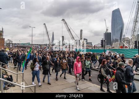 Demonstranten marschieren während der Demonstration entlang der Themse.eine große Zahl von Demonstranten versammelten sich im Zentrum von London, um gegen die Anwendung von Sperrungen in Großbritannien und die Umsetzung des Polizeigesetzes zu protestieren. Die Demonstration markiert ein Jahr seit dem Eintritt des Vereinigten Königreichs in seine erste Sperre, die für "drei Wochen geplant war, um die Kurve zu glätten und den NHS zu schützen". Die konservative Regierung ist unter großem Druck der Öffentlichkeit geraten, die Sperren zu beenden, trotz der Befürchtungen, dass Coronavirus-Fälle zunehmen könnten. Die Demonstration wird 10 Downing Street alarmiert haben, die die Aussicht auf einen Summ fürchten würde Stockfoto