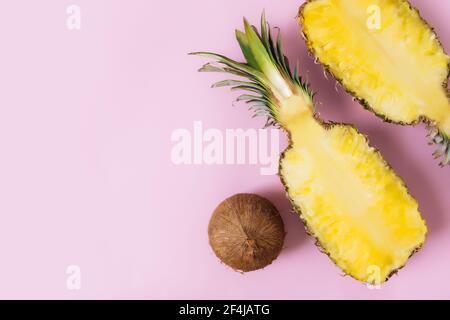 Schneiden Sie Hälften von frischer Ananas, Kokosnuss auf pastellrosa Hintergrund. Exotische Früchte Stockfoto