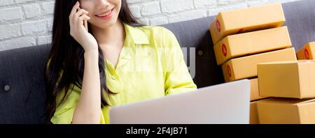 Junge asiatische Frau ist Unternehmer im Gespräch mit Kunden und mit Laptop-Computer, während Bestellung online zu Hause kaufen, Logistik und Lieferung, online s Stockfoto
