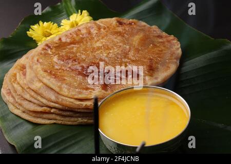 Puran Poli, auch bekannt als Holige, ist ein indisches süßes Fladenbrot aus Indien, das meistens während des Holi-Festivals konsumiert wird. Serviert auf Bananenblatt mit reinem Ghee o Stockfoto