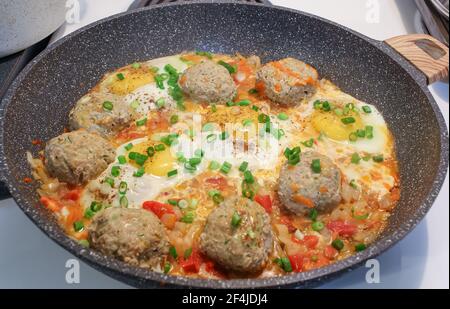 Keto-Diät. Hausgemachtes Frühstück mit gebratenen Fleischbällchen, Tomaten, Frühlingszwiebeln, Eiern in der Pfanne. Keto, Paleo Food. Stockfoto