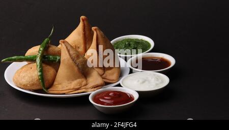 Kachori und Samosa, indische vegetarische Snacks mit grünen und Tamarinden-Chutneys. Stockfoto