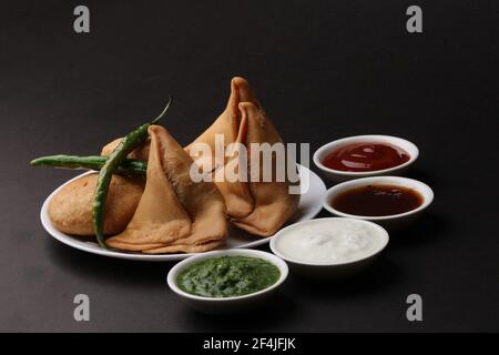 Kachori und Samosa, indische vegetarische Snacks mit grünen und Tamarinden-Chutneys. Stockfoto