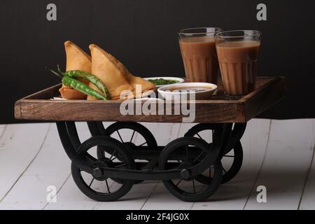 Indische Snack hausgemachte würzige und köstliche Samosa serviert mit grünen, Tamarinde Chutney Schneiden Masala Tee, Chai, Stockfoto