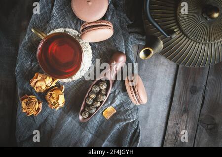 Fermentierter chinesischer Tee in einer keramischen Kugel mit Mandelgebäck auf dem Hintergrund eines Holztisches mit einer Tasse Tee. Selektiver Fokus. Draufsicht. Stockfoto