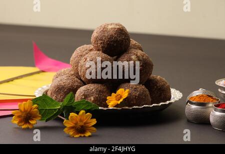Til Gul ODER Sweet Sesam Laddu mit Drachenmodell, haldi Kumkum und Zuckerkristallen für das Makar Sankranti Festival auf schwarzem Hintergrund. Stockfoto