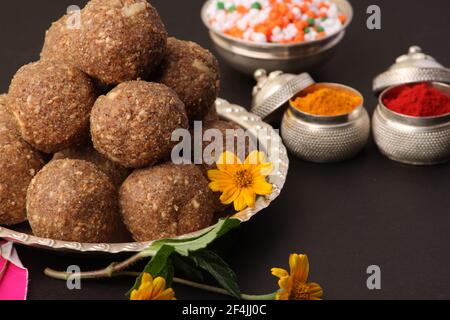 Til Gul ODER Sweet Sesam Laddu mit Drachenmodell, haldi Kumkum und Zuckerkristallen für das Makar Sankranti Festival auf schwarzem Hintergrund. Stockfoto