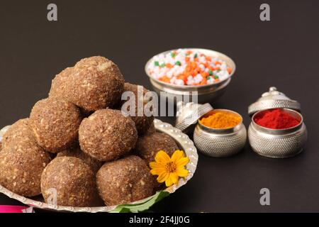 Til Gul ODER Sweet Sesam Laddu mit Drachenmodell, haldi Kumkum und Zuckerkristallen für das Makar Sankranti Festival auf schwarzem Hintergrund. Stockfoto