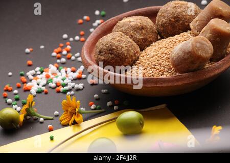 Til Gul ODER Sweet Sesam Laddu mit Drachenmodell, haldi Kumkum und Zuckerkristallen für das Makar Sankranti Festival auf schwarzem Hintergrund. Stockfoto