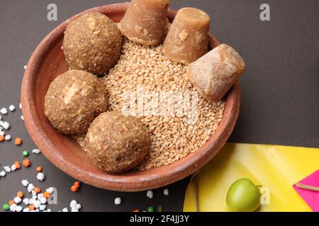 Til Gul ODER Sweet Sesam Laddu mit Drachenmodell, haldi Kumkum und Zuckerkristallen für das Makar Sankranti Festival auf schwarzem Hintergrund. Stockfoto