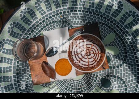 Eine Reihe von heißen Kaffeegetränken auf einem Keramiktisch platziert. Der Hintergrund eines Wasserfalls, üppiges Grün und Dampf schwebten heraus, um es frisch aussehen zu lassen. Stockfoto