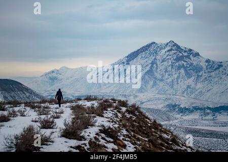 Unbekannte Person, die am Ufer des Azat-Stausees in Armenien entlang wandert, mit dem Berg Yeranos im Hintergrund Stockfoto