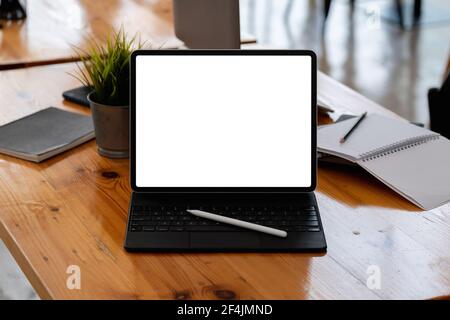 Kurze Aufnahme des Arbeitsplatzes mit leerem Tablet-Bildschirm und Büro Verbrauchsmaterial in einem einfachen Arbeitsbereich Stockfoto