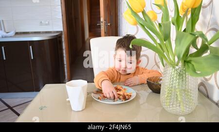 Das Kind isst alleine am Tisch. Hochwertige Fotos Stockfoto