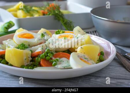 Gekochte Eier mit Gemüse, Kartoffeln und Sauce auf einem Teller Stockfoto