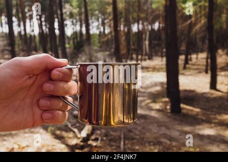 Man's Hand hält Edelstahl Tasse mit heißem Tee Nahaufnahme. Stockfoto