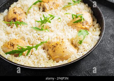 Reis mit Hähnchenschenkeln, Pilaf in Pfanne auf dunklem Hintergrund. Stockfoto