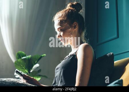 Seitenansicht Foto einer kaukasischen Ingwer Frau, die Papier trägt Maske liegt im Bett Stockfoto