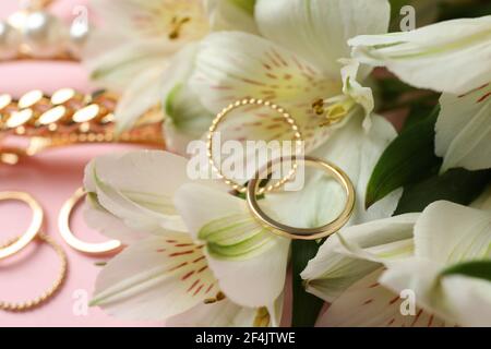 Schmuck und Blumen auf rosa Hintergrund, Nahaufnahme Stockfoto