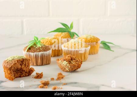 Marihuana Cupcake Muffins und Cannabisblätter auf einem weißen Marmortisch. Hausgemachte Speisen. Stockfoto